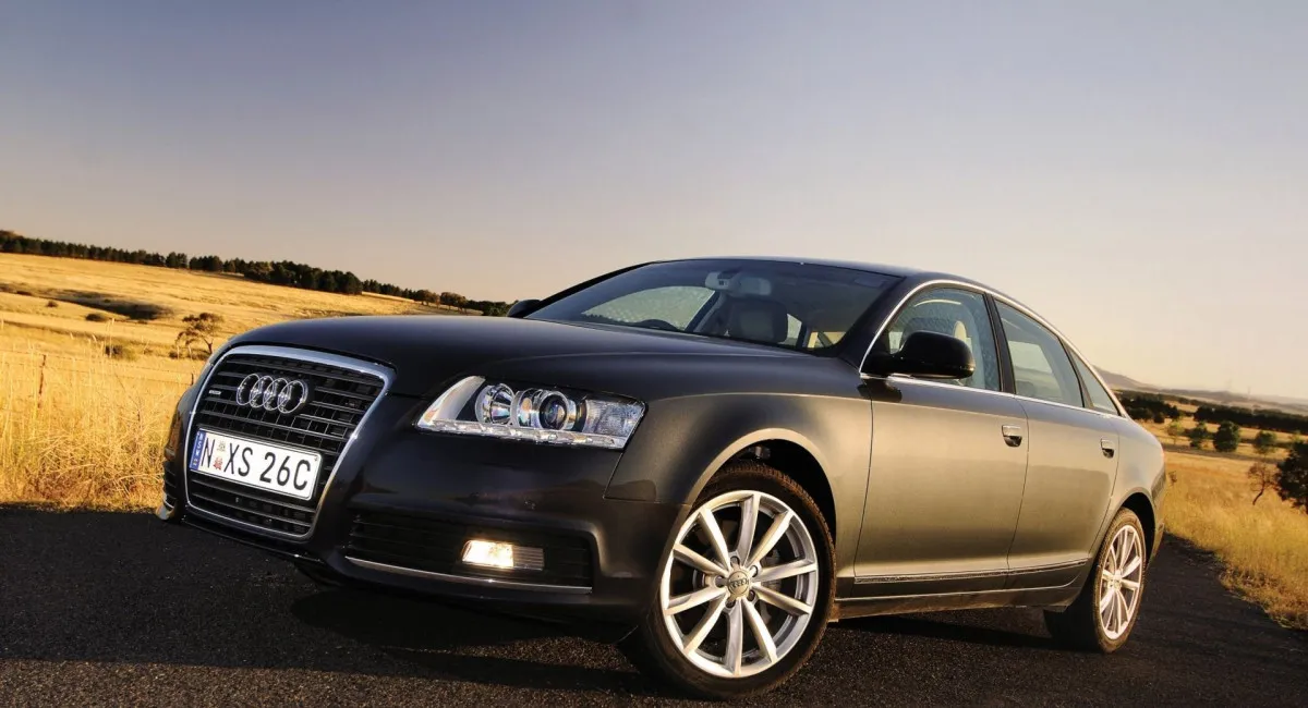 Чорний седан Audi на дорозі в сільській місцевості.